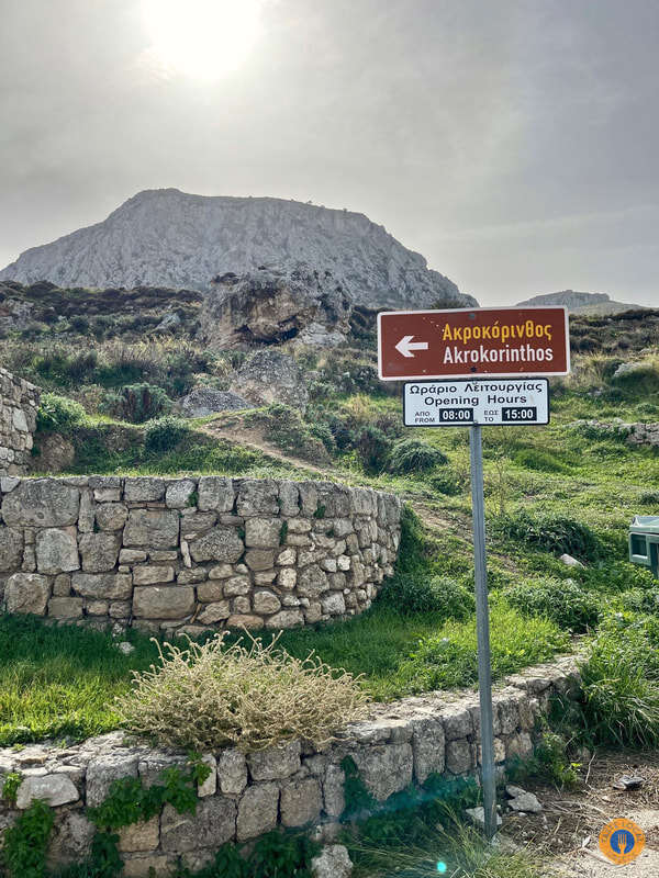 Akrocorinthos, the biggest ancient fortress of the Peloponnese. - Gastronomy Tours a sign on a pole in a grassy area in Akrokorinthos